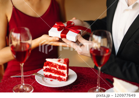 Couple in love exchanges gifts. Handsome man and woman on a date in a restaurant. Concept of love. 120977649