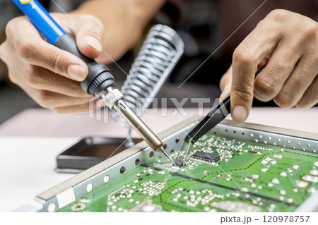 Man technician soldering a electric circuit board 120978757