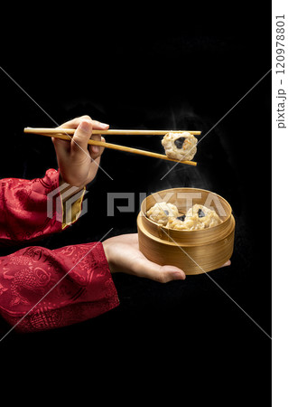 Chinese person with chopstick eating dim sum dumpling on bamboo wooden basket bowl 120978801