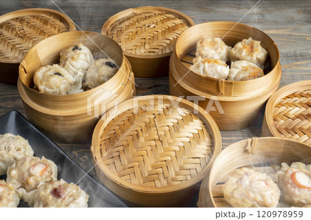 Assorted chinese dim sum dumpling on the plate with bamboo wooden basket bowl on wooden table 120978959