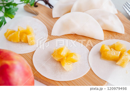煮リンゴを餃子の皮で包んでいく 120979498