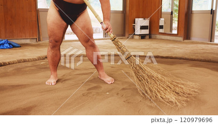 Broom, dohyo and legs of Sumo wrestler sweeping sand in mawashi, getting ready for competition. Cleaning, preparation and start with person in Japan for culture, heritage or martial arts tradition 120979696
