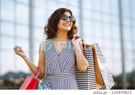 Shopping time. Young woman with shopping bags near the mall. Consumerism, sale, purchases. 120979923