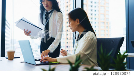 Office, business women and laptop with colleague, team or assistant as executive or professional. Female people, paperwork and technology in collaboration, discussion or company for law firm in Japan 120980074