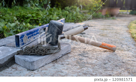 Laying paving stones on cement mortar. Laying a garden path made of tiles. Self-laying of concrete paving slabs in the courtyard of the house. do it yourself. DIY 120981571