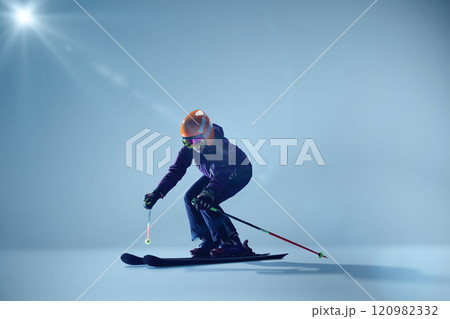 Young woman, sport lover, kier crouches in action pose, ready to glide, against gradient blue studio background. 120982332