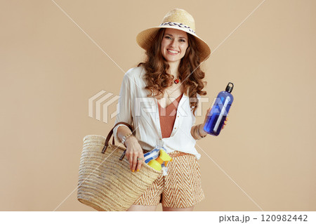 smiling stylish woman in blouse and shorts isolated on beige 120982442