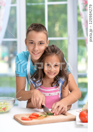 Cute little brother and sister preparing salad together at kitchen Cute little brother and sister preparing salad together at kitchen 120984279