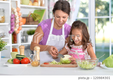 Mother and daughter preparing salad with daughter in the kitchen 120984301