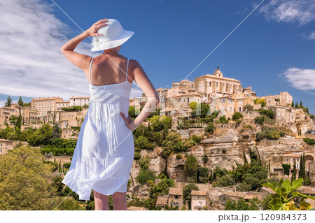 Woman in summer dress on vacation looking at the village of Gordes in Luberon, Provence, France 120984373