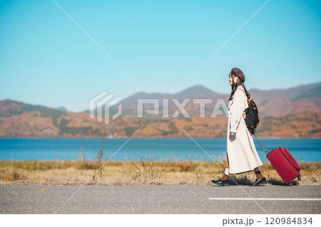 女子旅　キャリーバックを持って青空のもと歩いている若い女性 120984834