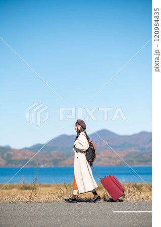 女子旅 キャリーバックを持って青空のもと歩いている若い女性 女子旅 キャリーバックを持って青空のもと歩いている若い女性 120984835