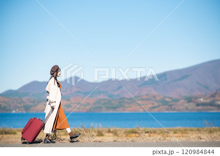 女子旅　キャリーバックを持って青空のもと歩いている若い女性 120984844