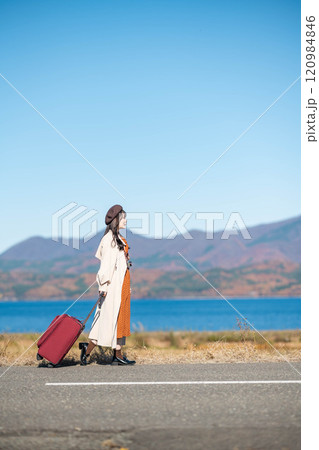 女子旅　キャリーバックを持って青空のもと歩いている若い女性 120984846