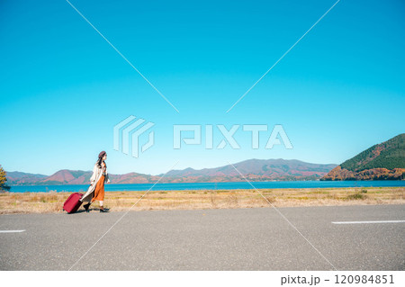 女子旅　キャリーバックを持って青空のもと歩いている若い女性 120984851