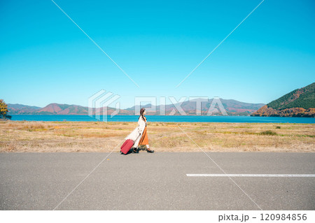 女子旅　キャリーバックを持って青空のもと歩いている若い女性 120984856