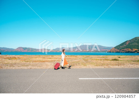 女子旅　キャリーバックを持って青空のもと歩いている若い女性 120984857