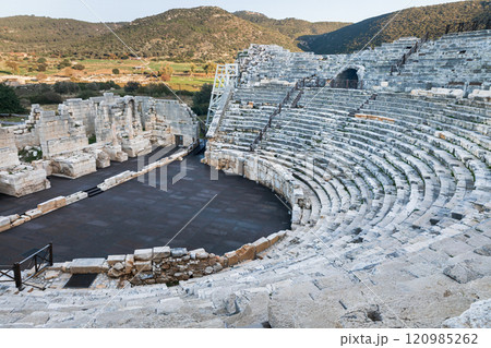 Ancient ruins of historical Patara city with old greek amphitheater and sunny Mediterranean landscape with distant hills. History and adventure on summer Turkish holidays. Lycian way, Antalya, Turkey Ancient ruins of historical Patara city with old greek amphitheater and sunny Mediterranean landscape with distant hills. History and adventure on summer Turkish holidays. Lycian way, Antalya, Turkey 120985262