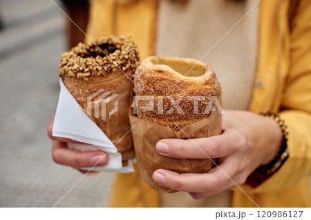 Woman holding two traditional chimney cakes at street of Prague, Czech Republic 120986127