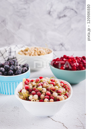 Assorted frozen red, white and black berries in bowls on table vertical view Assorted frozen red, white and black berries in bowls on table vertical view 120986880