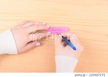 A blue pen in the hands of a young woman writes a note Thank you. A blue pen in the hands of a young woman writes a note Thank you. 120987275