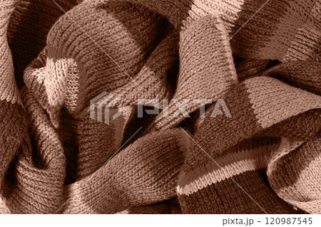 Demonstrating the colors of 2025 - Mocha Mousse. Knitted brown background. Large knitted fabric with a pattern. Close-up of a knitted blanket. Color concept. 120987545