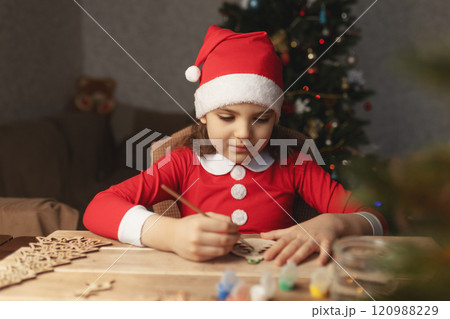 Pretty little girl in Santa Claus costume decorates Christmas toys at home Pretty little girl in Santa Claus costume decorates Christmas toys at home 120988229