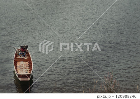 Traditional hand built small wooden rowboat slowly in warm evening light was resting along in the dam. 120988246