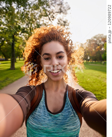 Young Woman Taking a Candid Selfie at Golden Hour in a Park 120989722