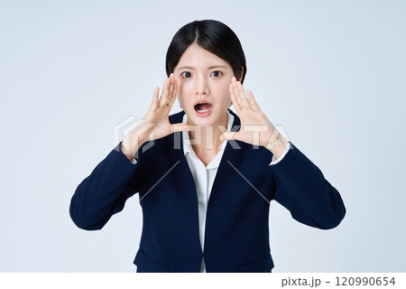 両手を顔に添えて大声を出すポーズをするビジネスウーマン 両手を顔に添えて大声を出すポーズをするビジネスウーマン 120990654