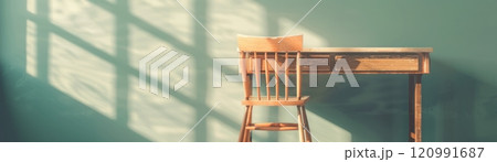 Sunlight streams through a window, casting shadows on a wooden chair and desk. 120991687