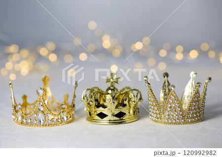 Epiphany Day or Dia de Reyes Magos concept. Three gold crowns on light sparkling background 120992982