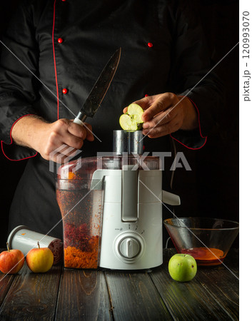 An experienced chef prepares fresh apple juice, showcasing the vibrant fruits and elegant juicer. The culinary space exudes warmth and creativity, inviting a healthy lifestyle 120993070