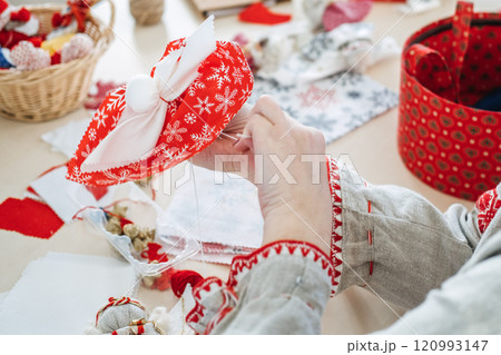 Handmaking holiday decor with red and white fabric. Showcasing festive cultural crafts and Slavic-inspired sewing traditions. Handmaking holiday decor with red and white fabric. Showcasing festive cultural crafts and Slavic-inspired sewing traditions. 120993147