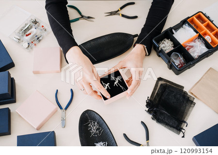 Hands presenting handmade earrings in a gift box. Showcasing sustainable jewelry design, eco-conscious packaging, and ethical craftsmanship. Hands presenting handmade earrings in a gift box. Showcasing sustainable jewelry design, eco-conscious packaging, and ethical craftsmanship. 120993154