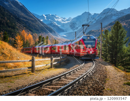 Red modern electric train traveling in alpine mountains in autumn Red modern electric train traveling in alpine mountains in autumn 120993547