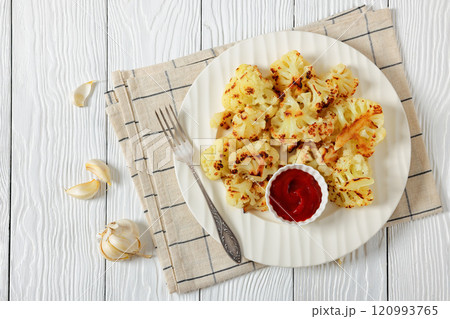 fried cauliflower florets on white plate, top view 120993765