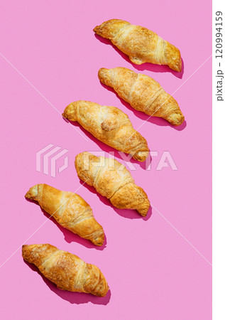 Flat lay of  fresh croissants on pink background with shadow. Creative layout 120994159