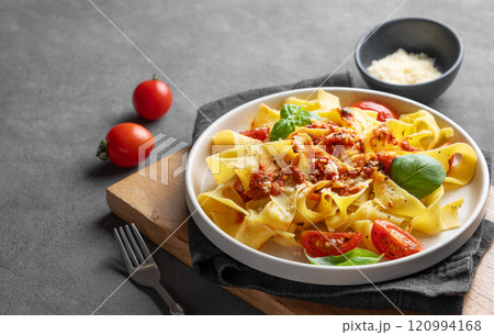 Tagliatelle pasta with tomato sauce, basil and parmesan cheese in a plate on a wooden board Tagliatelle pasta with tomato sauce, basil and parmesan cheese in a plate on a wooden board 120994168