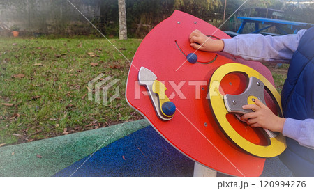 Large children's sensory toys on the playground and the child who plays with them. Concept of development of fine motor skills, Montesori for children outdoors Large children's sensory toys on the playground and the child who plays with them. Concept of development of fine motor skills, Montesori for children outdoors 120994276