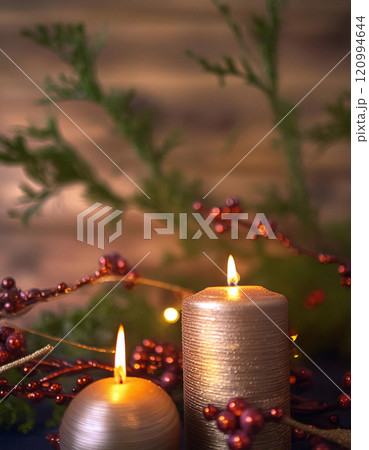 Two candles glow warmly amidst festive greenery and red berries 120994644