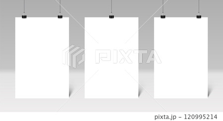 Three blank vertical posters hanging from binder clips on a gray wall create an ideal setting for displaying artwork or designs, enhancing any creative environment or presentation space 120995214