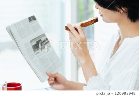 食事中に新聞を読む女性 120995949