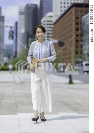 オフィス街で手帳を手に持つビジネスウーマンのポートレート　縦位置 120996613