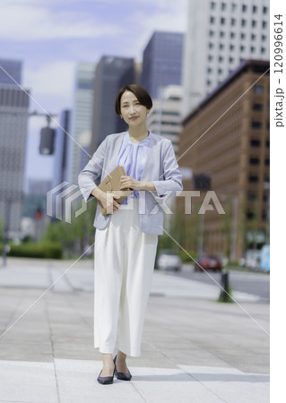 オフィス街で手帳を手に持つビジネスウーマンのポートレート　縦位置 120996614