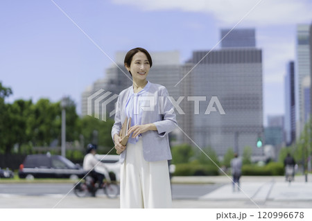 手帳を手にオフィス街を歩くビジネスウーマンのポートレート 120996678