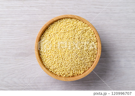 Organic yellow millet grain in wooden bowl on white table, Healthy food ingredient, Top view Organic yellow millet grain in wooden bowl on white table, Healthy food ingredient, Top view 120996707