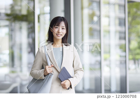 スマートフォンと資料を手に立つ笑顔の女性会社員 121000708