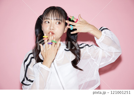 ピンク背景で撮影をしたスポーティな服装をした若い女性のキュートなポートレート 121001251