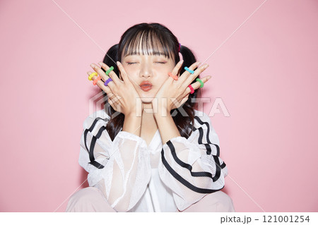 ピンク背景で撮影をしたスポーティな服装をした若い女性のキュートなポートレート 121001254